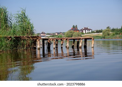 Old wooden pier on river. Bridge over calm water. Abandoned pier for fisherman. Fishing pond. Relax