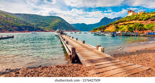 Old Wooden Pier In Port De Girolata - Place, Where You Can't Get By Car. Panoramic Summer View Of Girolata  Port, Corsica Island, France. Beautiful Mediterranean Seascape. Traveling Concept Background