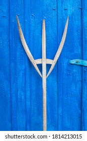 Old Wooden Pitchfork Leaning On Blue Barn Door