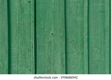 Old wooden planks, arranged vertically, painted with spring green paint, cracked and faded in the sun. Wood texture. Textured background.