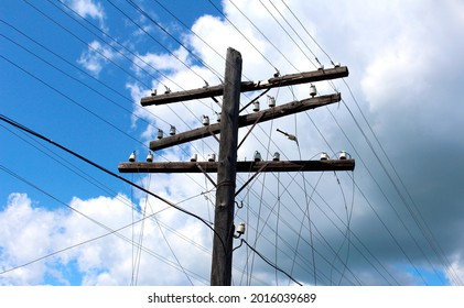 Old Wooden Pole With Hanging Electrical Wires Against The Background Of Clouds