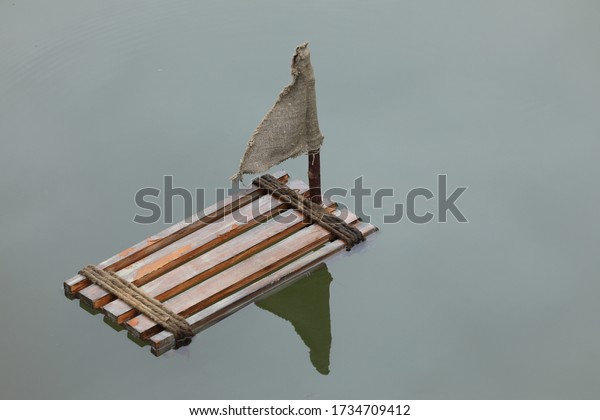 old wooden raft\
floating on the water
