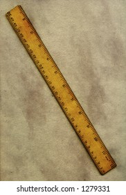 An Old Wooden Ruler Lying On A Piece Of Grubby Old Paper.