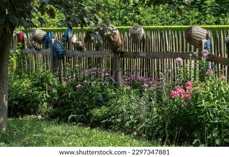 old, wooden, rural fence with farm utensils and planted with flowers