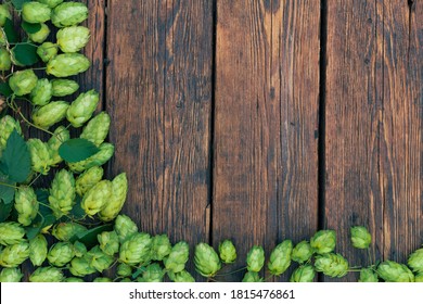 Old wooden rustic table surface with fresh green hops.