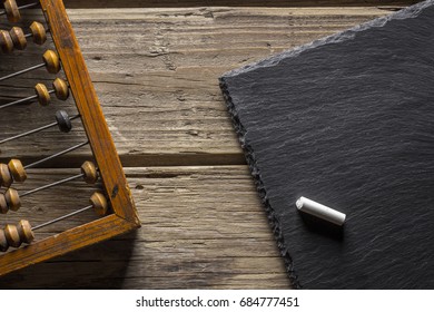 Old Wooden Scratched Vintage Decimal Abacus And Blank Blackboard With Copy Space And Chalk On A Wooden Desktop . Top View. Flat Lay. Mockup