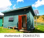 An old wooden shed equipped with solar panels, utilizing renewable energy in a rural setting