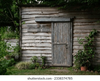 A old wooden shed, in the middle of a lovely garden, with a sign that means 