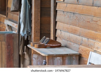 Old Wooden Shoebox Near A Wooden Cottage On A Farm. The Shoe Box Has Old Clogs, Rubber Boots And Shoes.