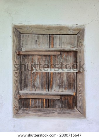 Old wooden shutter window with rustic iron latch on a traditional rural house. Weathered wood texture and details of vernacular architecture