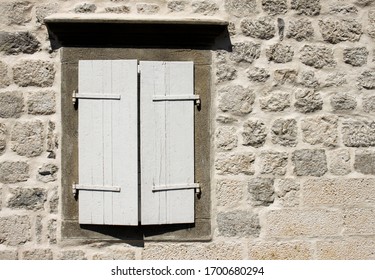 Old wooden shutters on ancient stone wall