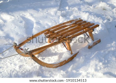 Old wooden sledge in the fresh snow. Winter sports, vacations and games concept concept. Sled with rope