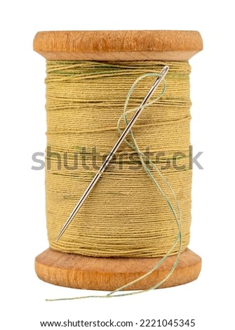 An old wooden spool of thread and a needle on a white background close-up. Threads for sewing