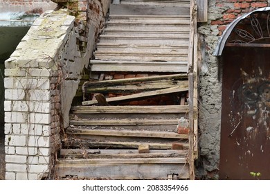 An old wooden staircase with broken steps in an abandoned house.