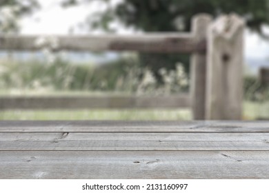 Old Wooden Table In A Field Or Park At The Countryside, With A Blurred Wooden Fence In The Background. Place A Digital Product Mockup Onto The Background.