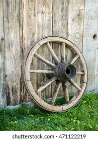 Old wooden wagon wheel resting against rustic wooden fence