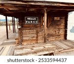 Old wooden Wells Fargo building with rustic charm, set against a backdrop of mountains and desert landscape.