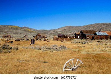 Old wooden wheel lying lonely in the dry grass near the abandoned gold mining town Bodie in California. USA