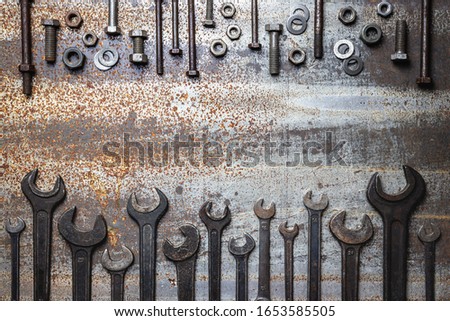 Old work tools and screws on rusty metal table. Top view variation of vintage wrenches and dirty bolt and nut fastener. Flat lay with copy space