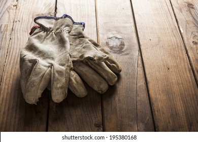 Old working gloves over wooden table, construction tools