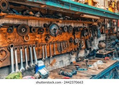Old workshop with tools. Wrenches and grinding wheel hang on wall. Repair items on table and shelve