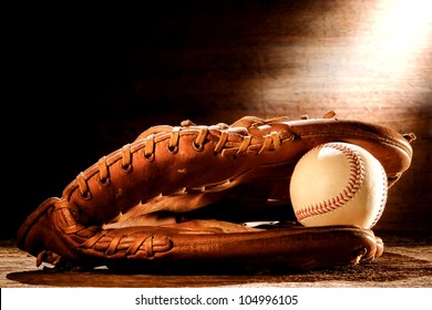 Old Worn Leather Baseball Catcher Sport Glove And Aged Stitched Ball On Antique Wood Boards In Soft Nostalgic Americana Light