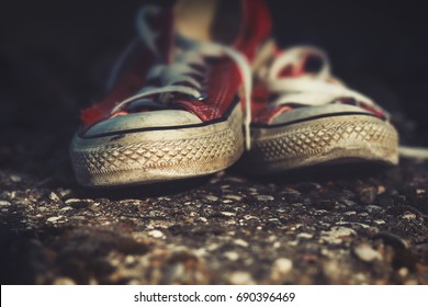 Old, Worn Out, Red Canvas Sneakers On A Concrete Path