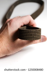 The old worn out rubber alternator belt in men's hand. The concept of car maintenance. Vertical photo