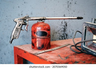 Old Worn Red Metal Oiler Pump On The Counter Of A Car Repair Workshop.