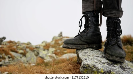 Old and worn Trekking Shoes, closeup of Traveler legs on the rock, hiking in the mountains 