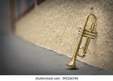 Old worn trumpet stands alone against a grungy wall