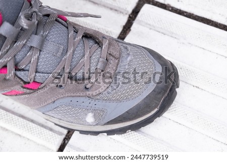 old worn-out shoes, hiking boots on female foot on floor, signs of wear and tear, adding to character, Poverty and Homelessness, Many miles walked on worn-out sneakers [[stock_photo]] © 
