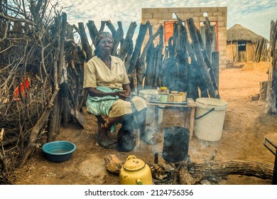 Old Wrinkled African Woman Sited In The Outdoor Kitchen Making Tea In A Village In Botswana