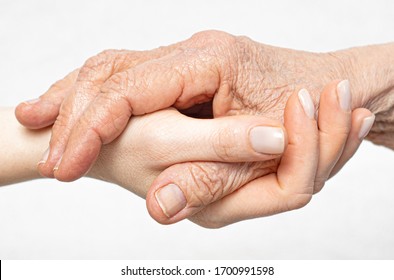 Old wrinkled hand lies on the young hand close-up. Helping for the elderly concept. 