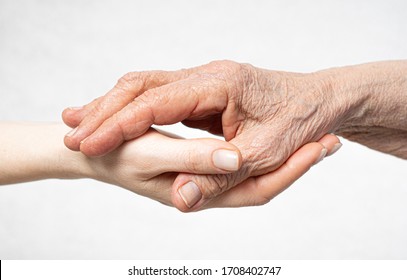 Old Wrinkled Hand Lies On The Young Hand. Care For Old People Concept. 