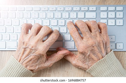 Old Wrinkled Hands On The Computer Keyboard. 