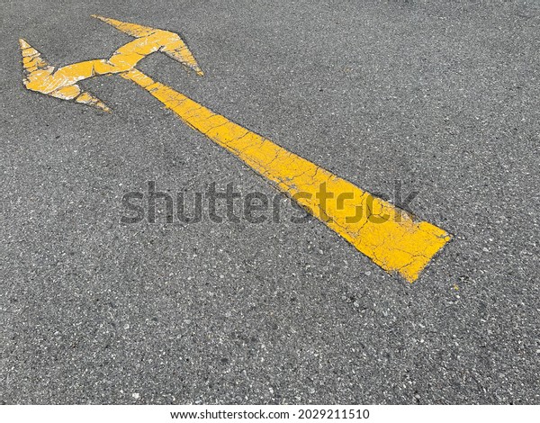 Old yellow\
arrow traffic sign on the road\
surface.