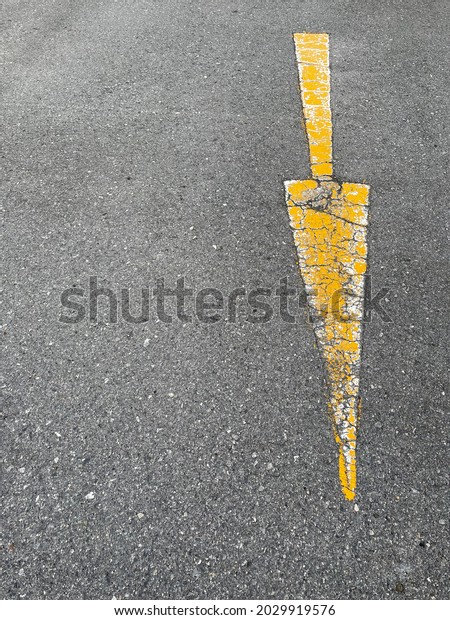 Old yellow\
arrow traffic sign on the road\
surface.