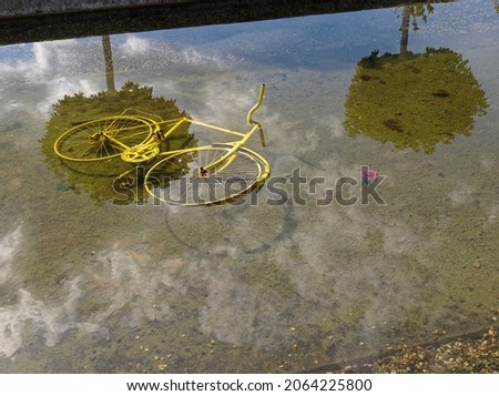 Old yellow bicycle lies in a pond