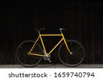 Old yellow bike against dark wood wall. Yellow singlespeed bike. Yellow single speed Favorite bike.