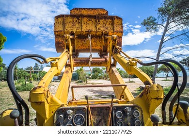 Old Yellow Broken Bulldozer. Construction Machinery With Trees In The Background