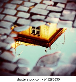 Old Yellow House In Reflection Of Puddle On Pavement. European Vintage City View. Cozy Street