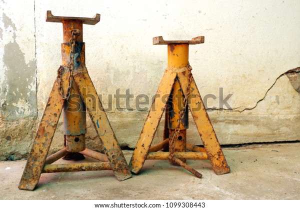 Old yellow jack stands steel for lift up car on\
cement floor with space
