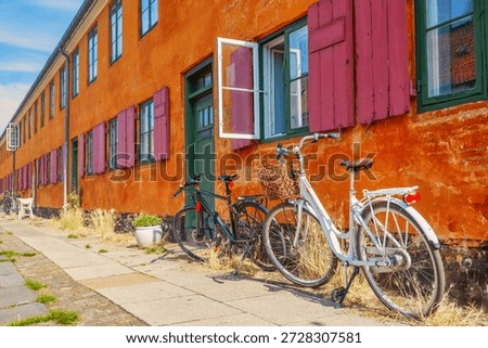 Old yellow orange house of Nyboder district with bicycles. Old Medieval district in Copenhagen, Denmark. Summer sunny day.