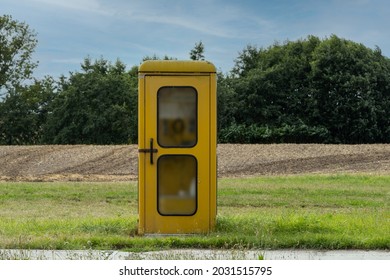 old yellow phone booth on a meadow outside the city