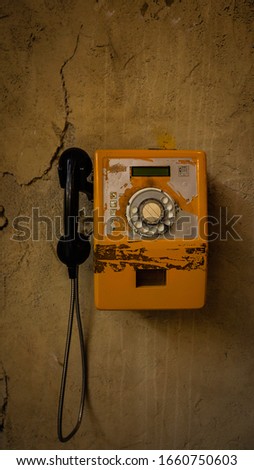 Old Yellow Vintage and Grungy Phone hanged on a grungy wall 