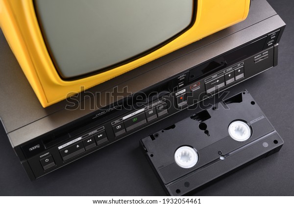 Old yellow vintage TV with\
VCR and videotape on black background from 1980s, 1990s, 2000s.\
Stack.