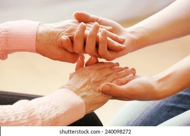 Old And Young Holding Hands On Light Background, Closeup