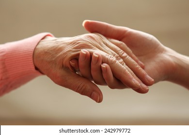 Old And Young Holding Hands On Light Background, Closeup