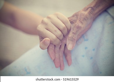 Old And Young Holding Hands On Light Background, Vintage Tone.